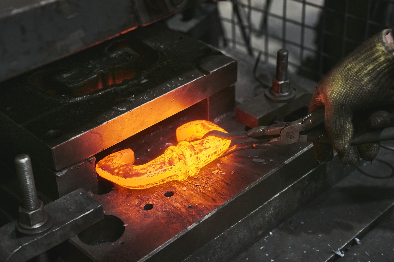 Operario manipulando pieza al rojo vivo